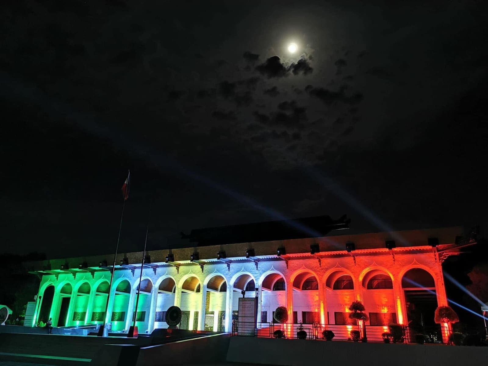 The arcade of the Bangsamoro Government Center at night, lit in bands of coloured light.