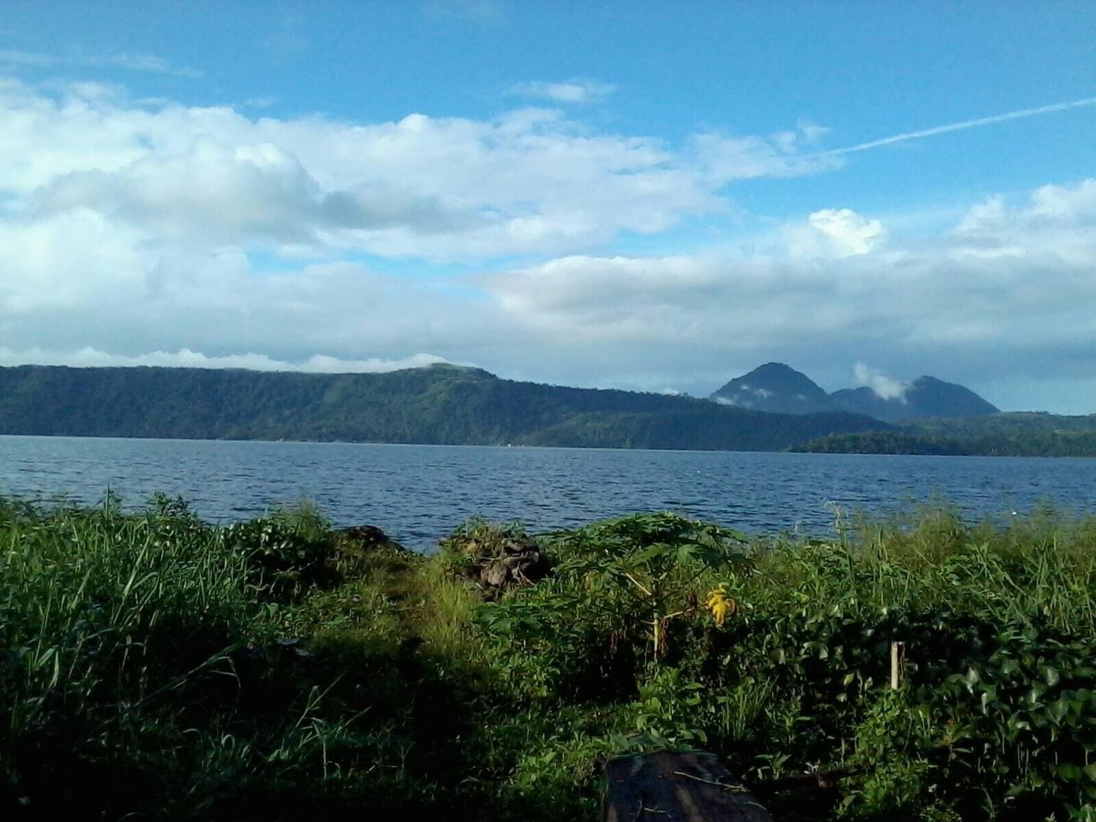 Lake Lanao stretching to distant hills under a bright, clouded sky.