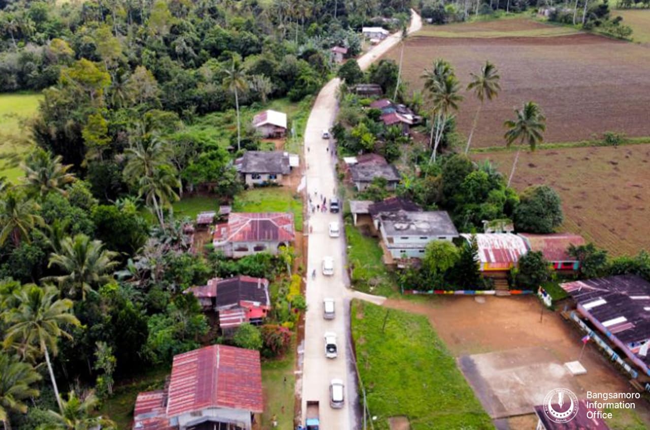 Aerial view of a newly concreted road through a village in Lumbayanague