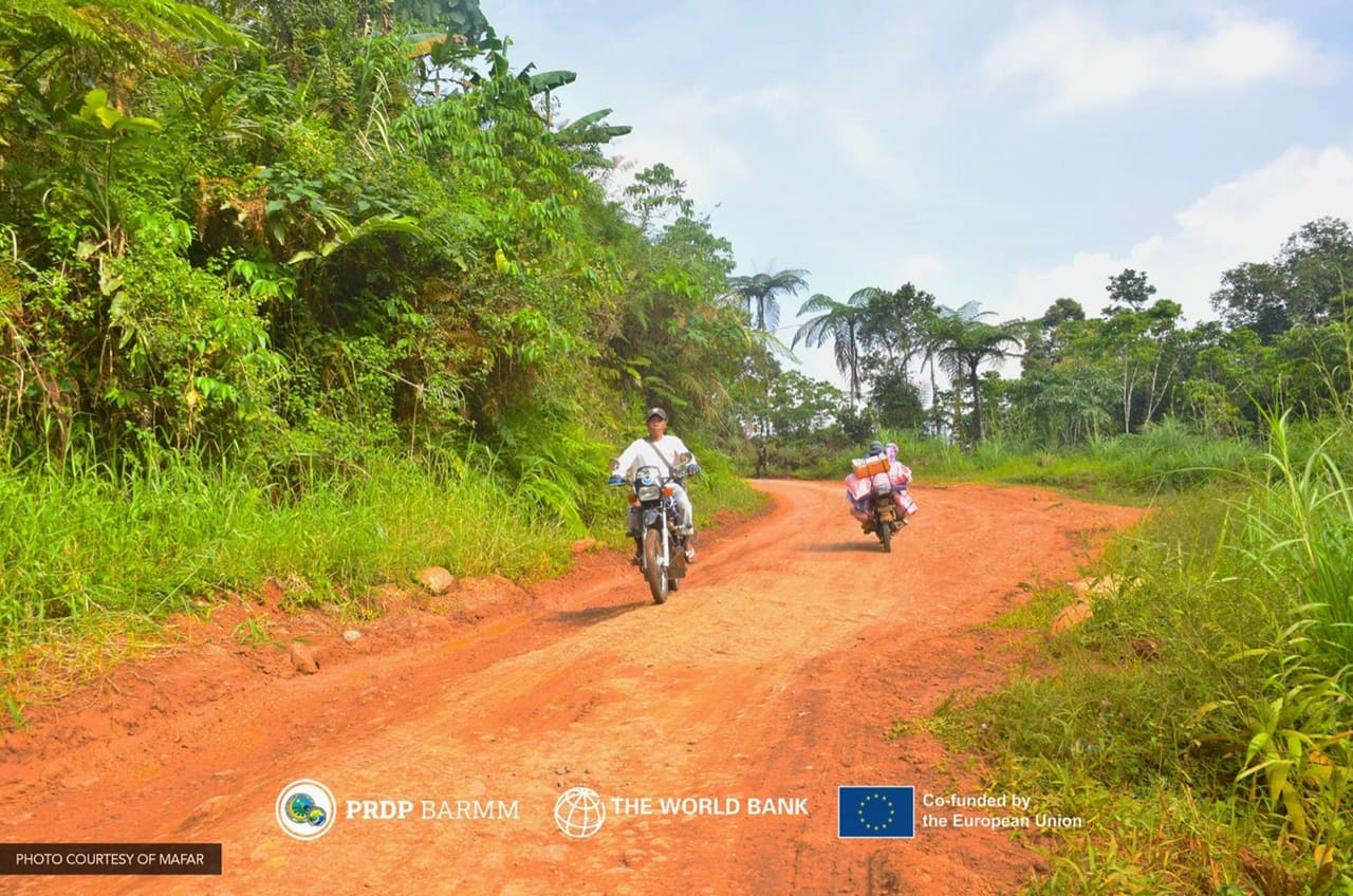 Motorcycles on a red-earth farm-to-market road in the inner barangays of South Upi